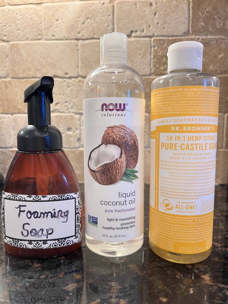 Foaming soap dispenser, liquid coconut oil, and castile soap on a counter