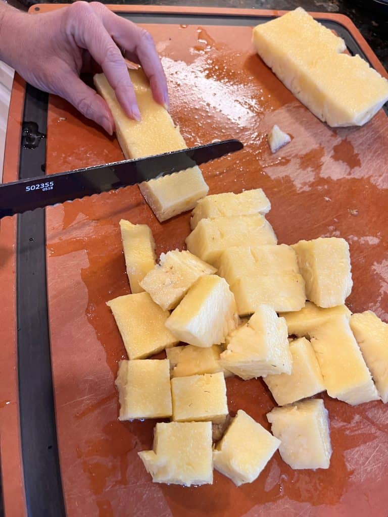Peeled pineapple being cut into small pieces