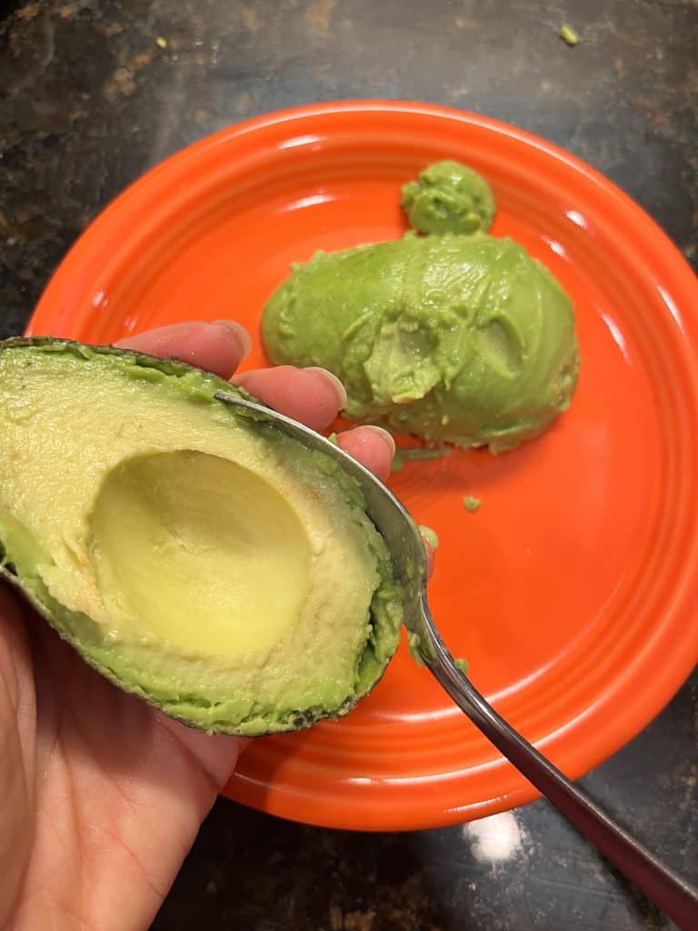 Spoon scooping out avocado flesh
