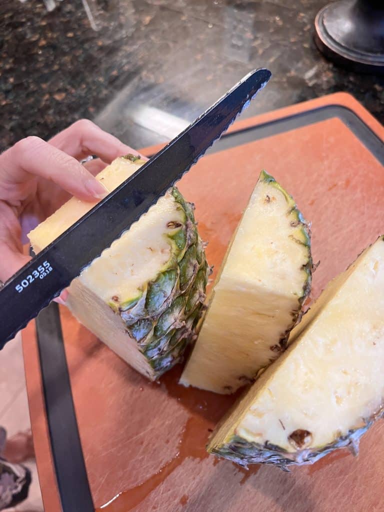 Pineapple being cut along core