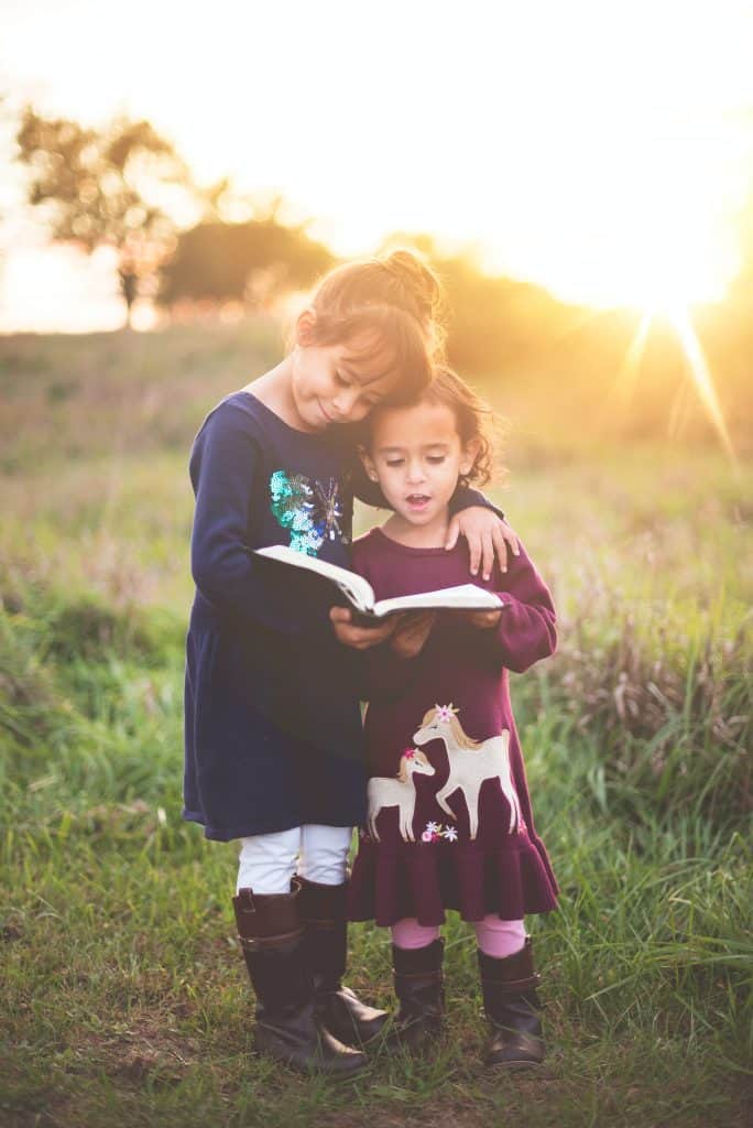 two girls hugging and reading their Bible